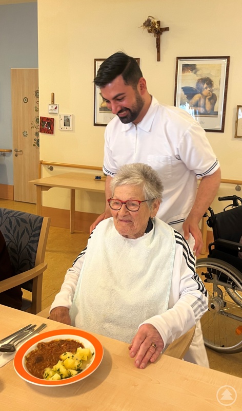 Muhanad Al-Halak serviert Bewohnerin Paula Kubis das Mittagessen.